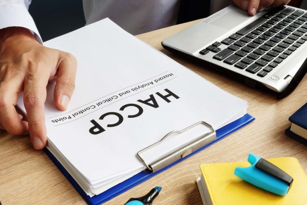 clipboard with HACCP document and laptop on desk