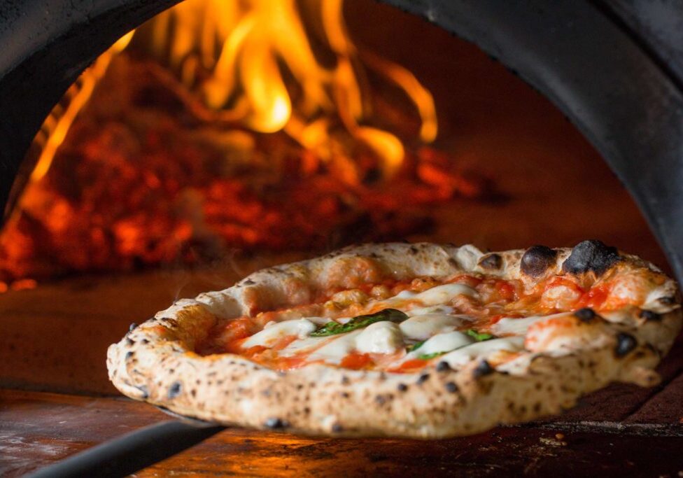 margherita pizza coming out of wood fired oven